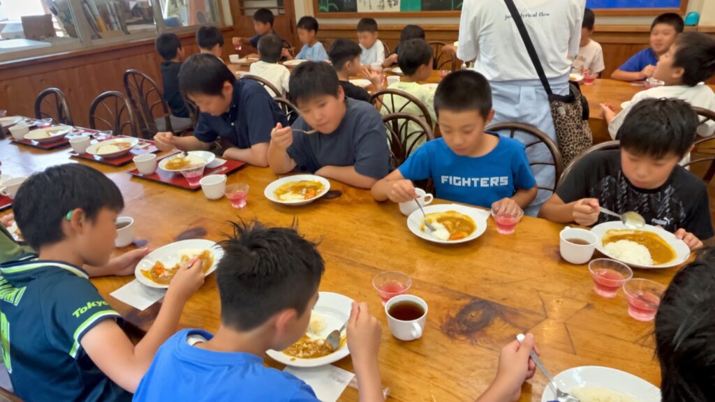 テーブルを囲んで養沢カレーを食べる選手たち