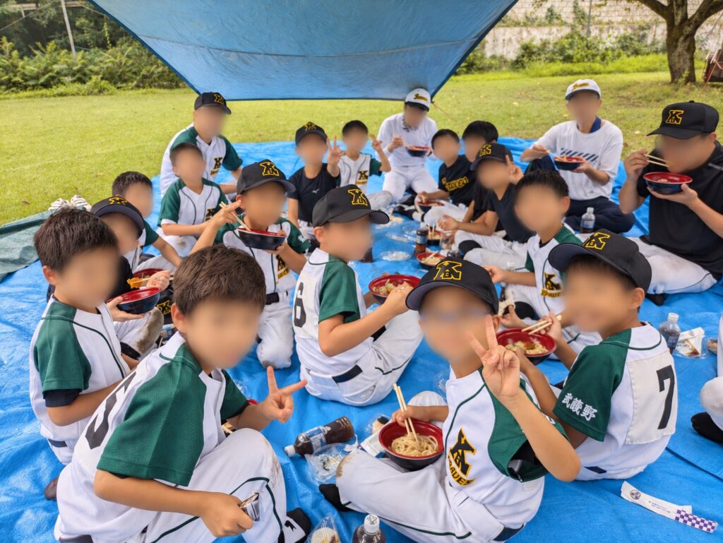 シートの上で一緒に昼食をとる選手と指導者たち