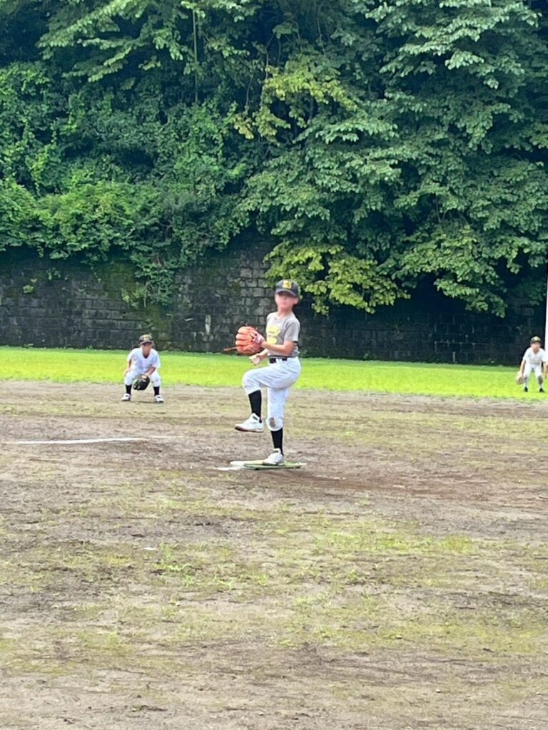 戸倉運動場で投球する選手と守備につく仲間たち